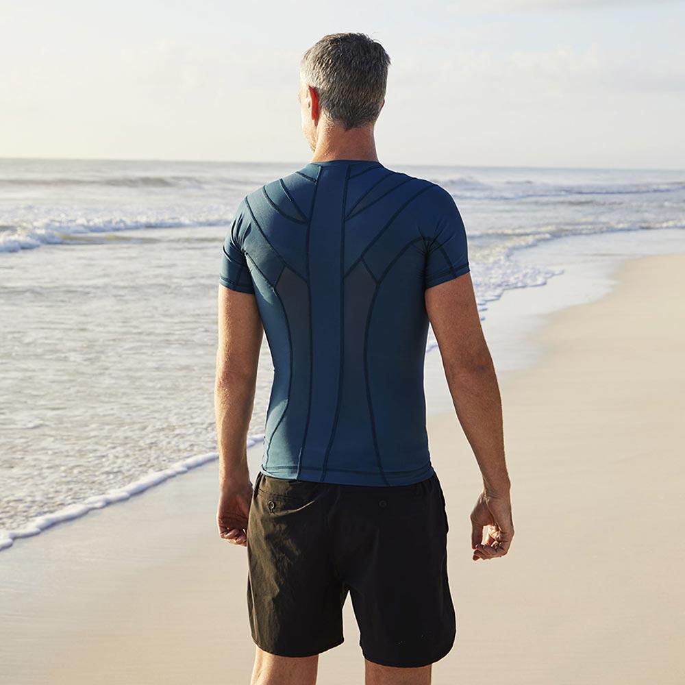 homme en t shirt mal du dos sur la plage